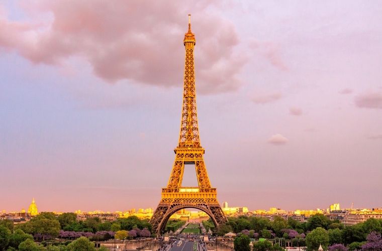 Paris’in simgesi olan Eiffel Kulesi, gökyüzüne doğru uzanırken etrafında parklarda yürüyen insanlar ve kuleye çıkan turistler görülüyor. Gündüz çekilen bu fotoğraf, kuleyi tam olarak görselleştiriyor.