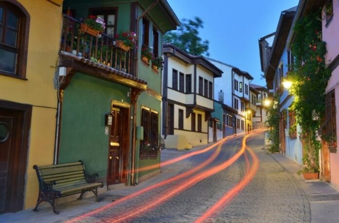 Eskişehir Porsuk Çayı üzerinde Venedik tipi gondol turu yapan insanlar ve arkada Adalar bölgesi manzarası.